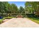 Expansive backyard featuring a patio, manicured landscaping, trees, and a pergola in the distance at 2283 Mays Chapel Rd, Sanford, NC 27330