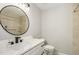 Neutral-toned bathroom with a round mirror, white sink and toilet at 2324 Dahlgreen Rd, Raleigh, NC 27615