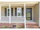 Inviting covered front porch with classic white railings and brick accents near the front door at 2324 Dahlgreen Rd, Raleigh, NC 27615