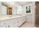 Well-lit bathroom with double sinks, white cabinetry, and a large mirror, featuring a tiled shower at 2629 Hiking Trl, Raleigh, NC 27615