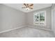 Cozy bedroom showcasing neutral walls, plush carpet, and a window with a backyard view at 2629 Hiking Trl, Raleigh, NC 27615