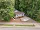Aerial view of a quaint blue house with a wooden deck surrounded by lush greenery and a paved driveway at 2704 Shaftsbury St, Durham, NC 27704