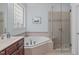 Bright bathroom showcasing a soaking tub with chrome hardware, a glass shower, and a granite vanity at 3104 Whitehart Ln, Apex, NC 27539