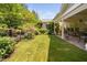 Serene backyard featuring a covered patio, manicured lawn, and lush garden with a black metal fence at 323 Rosedale Creek Dr, Durham, NC 27703