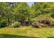 Beautiful backyard with lush green grass, a black metal fence, and mature trees and landscaping at 323 Rosedale Creek Dr, Durham, NC 27703