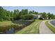 Beautiful home exterior with a retaining wall, black metal fence, pond, and lush landscaping at 323 Rosedale Creek Dr, Durham, NC 27703