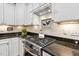 Close-up of a kitchen featuring a stainless steel gas range, granite countertop, and white cabinets at 323 Rosedale Creek Dr, Durham, NC 27703