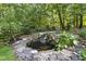 Backyard pond with rock waterfall surrounded by lush greenery and plants, creating a serene atmosphere at 3412 Paddock Cir, Raleigh, NC 27613
