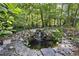 Backyard pond with a rock waterfall, lush greenery, and mature trees, creating a peaceful and natural oasis at 3412 Paddock Cir, Raleigh, NC 27613