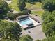 Aerial view of a community pool, white fencing, and clubhouse surrounded by a lush landscape at 3412 Paddock Cir, Raleigh, NC 27613