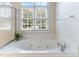 Bathroom with large soaking tub, tiled surround and natural light at 4305 Heathgate Ln, Raleigh, NC 27613