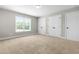A cozy bedroom with neutral walls, carpet, a window with natural light and three white doors at 4924 Zebulon Rd, Zebulon, NC 27597