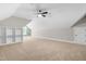 A spacious bonus room with built in shelving, carpet, a ceiling fan and lots of natural light at 4924 Zebulon Rd, Zebulon, NC 27597