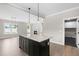 Kitchen island with granite counters and dark cabinets; open concept to living room and laundry at 4924 Zebulon Rd, Zebulon, NC 27597