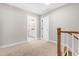 A bright upstairs hallway with carpet, a view to the bathroom and a wooden railing at 4924 Zebulon Rd, Zebulon, NC 27597