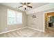 Bedroom with carpet, a ceiling fan, large window, and adjacent bathroom at 5305 Yorkville Ct, Holly Springs, NC 27540