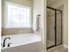 A bathroom featuring a tub under a window, and a glass-doored shower at 5400 Falconton Ln, Raleigh, NC 27610