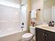 Bathroom with a white tub, matching toilet, and vanity with dark cabinets at 5400 Falconton Ln, Raleigh, NC 27610
