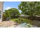 Backyard with a patio, green lawn, blooming flower pots, mature trees, and a wooden fence at 5561 Roan Mountain Pl, Raleigh, NC 27613