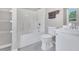Bright bathroom featuring a tub with shower, toilet, sink, and storage shelves, offering a clean and functional space at 5617 Tealbrook Dr, Raleigh, NC 27610