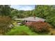 An elevated exterior view of a brick ranch featuring metal roof, mature trees and attached carport at 5918 Efland Cedar Grove Rd, Cedar Grove, NC 27231