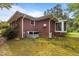 Back of brick house with central air, a sunroom, and lush landscaping at 5918 Efland Cedar Grove Rd, Cedar Grove, NC 27231