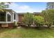 Brick home with a sunroom and blossoming bushes, creating a picturesque backyard setting at 5918 Efland Cedar Grove Rd, Cedar Grove, NC 27231