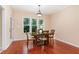 Cozy dining room with hardwood floors, a classic light fixture, and views of the backyard at 6717 Country Hollows Ln, Holly Springs, NC 27540