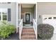 Close-up of front entrance with brick steps and black door, enhanced by potted plants at 6717 Country Hollows Ln, Holly Springs, NC 27540