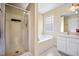Bright bathroom featuring a glass enclosed shower, soaking tub, and vanity with neutral countertops at 702 Calavaras Ln, Knightdale, NC 27545