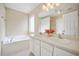 Bright bathroom with dual sinks, large mirror, garden tub and decorative lighting at 702 Calavaras Ln, Knightdale, NC 27545