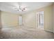 Large carpeted bedroom featuring neutral walls, ceiling fan and view into adjoining bathroom at 702 Calavaras Ln, Knightdale, NC 27545