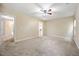 Large carpeted bedroom featuring neutral walls, ceiling fan and door to bathroom and walk-in closet at 702 Calavaras Ln, Knightdale, NC 27545