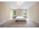 Bright bedroom featuring neutral carpet, beige walls, a comfortable bed and natural light from two windows at 702 Calavaras Ln, Knightdale, NC 27545