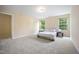 Bright bedroom featuring neutral carpet, beige walls, a comfortable bed and natural light from two windows at 702 Calavaras Ln, Knightdale, NC 27545