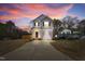 Charming two-story home with a well-manicured lawn and inviting curb appeal showcased by a colorful sunset at 717 Utley St, Holly Springs, NC 27540