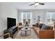 Sunlit living room with hardwood floors, modern furniture, and an entertainment center, perfect for relaxation and entertainment at 717 Utley St, Holly Springs, NC 27540