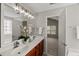 Bathroom featuring a double sink vanity and an open doorway leading to the carpeted bedroom at 7873 Cape Charles Dr, Raleigh, NC 27617