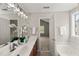 Bathroom featuring a double sink vanity with framed mirror and open doorway to bedroom and jacuzzi tub at 7873 Cape Charles Dr, Raleigh, NC 27617