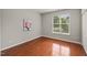 Clean bedroom showcasing gleaming hardwood floors and a large window with bright natural light at 7873 Cape Charles Dr, Raleigh, NC 27617