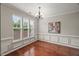 Dining room featuring hardwood floors, a modern chandelier, wainscoting, and plenty of natural light at 7873 Cape Charles Dr, Raleigh, NC 27617
