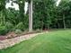 Beautifully landscaped backyard featuring a lush lawn, mature trees, and a charming rock garden at 83 Sawyer Ct, Wendell, NC 27591