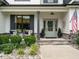 Inviting front porch with seating area, stone accents, American flag, and decorative potted plants at 83 Sawyer Ct, Wendell, NC 27591