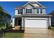 Two-story home featuring gray siding, stone accents, two-car garage, and well-manicured lawn at 88 Willow Cameron Way, Angier, NC 27501