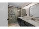 Bathroom featuring double sinks, granite countertops, black cabinets, and a tiled walk-in shower at 8808 Colesbury Dr, Raleigh, NC 27615
