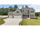 Charming two-story home featuring a three-car garage, landscaped yard, and covered front porch at 90 Lane Farms Way Way, Holly Springs, NC 27540