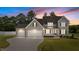Sunset view of a craftsman style home featuring a three-car garage and covered porch at 90 Lane Farms Way Way, Holly Springs, NC 27540
