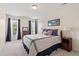 This is a bright bedroom with a queen bed, soft lighting, two windows with blue curtains and a carpeted floor at 1001 Pasture View Ln, Raleigh, NC 27603