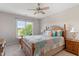 Cozy bedroom featuring a patterned bedspread, bedside tables, a ceiling fan, and a large window overlooking a lawn at 1001 Pasture View Ln, Raleigh, NC 27603