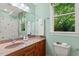 Bright bathroom with wood vanity, framed mirror, and a large window overlooking the backyard at 101 Cardiff Pl, Chapel Hill, NC 27516